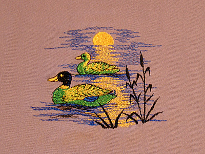 Broderie d'un motif "Canards" 8 x 8 cm en 4 couleurs sur T-shirt couleur chair.