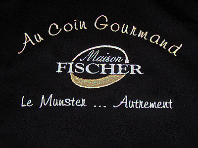 Broderie 18 x 12 cm en blanc et beige sur tablier noir pour la fromagerie Fischer